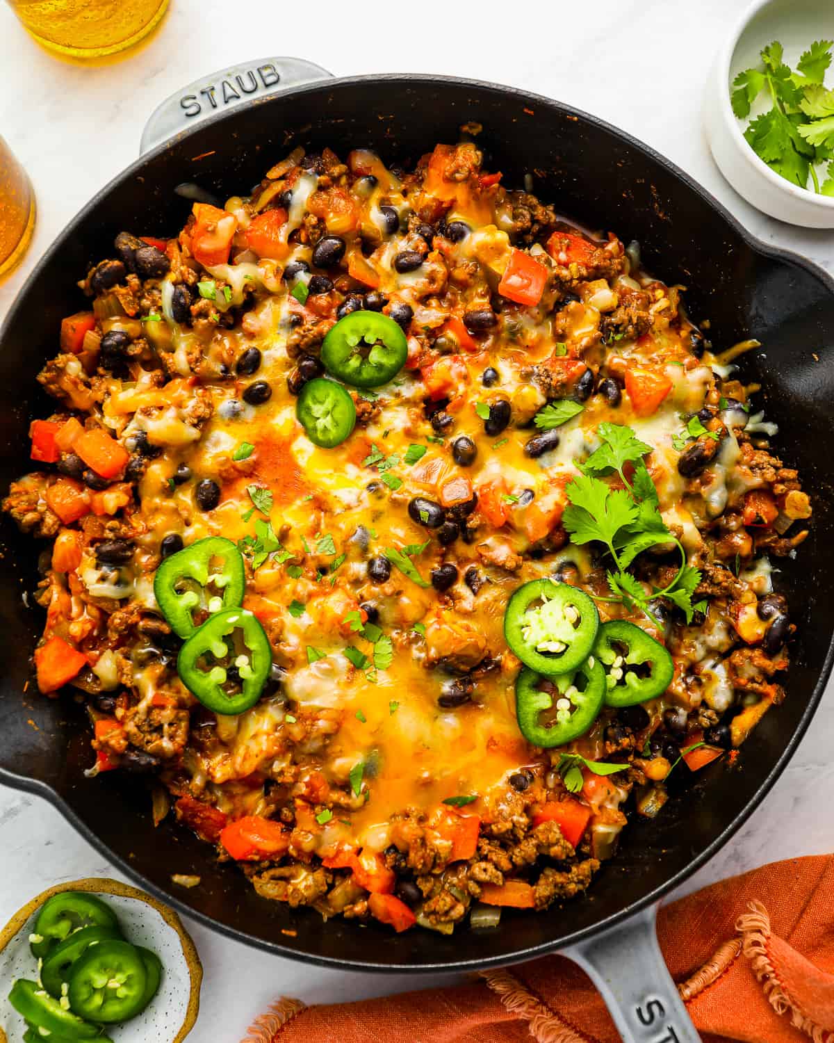 a taco skillet full of cheesy mexican rice with black beans and jalapenos.