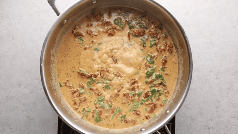 A Tuscan Chicken soup simmering on a stove top.