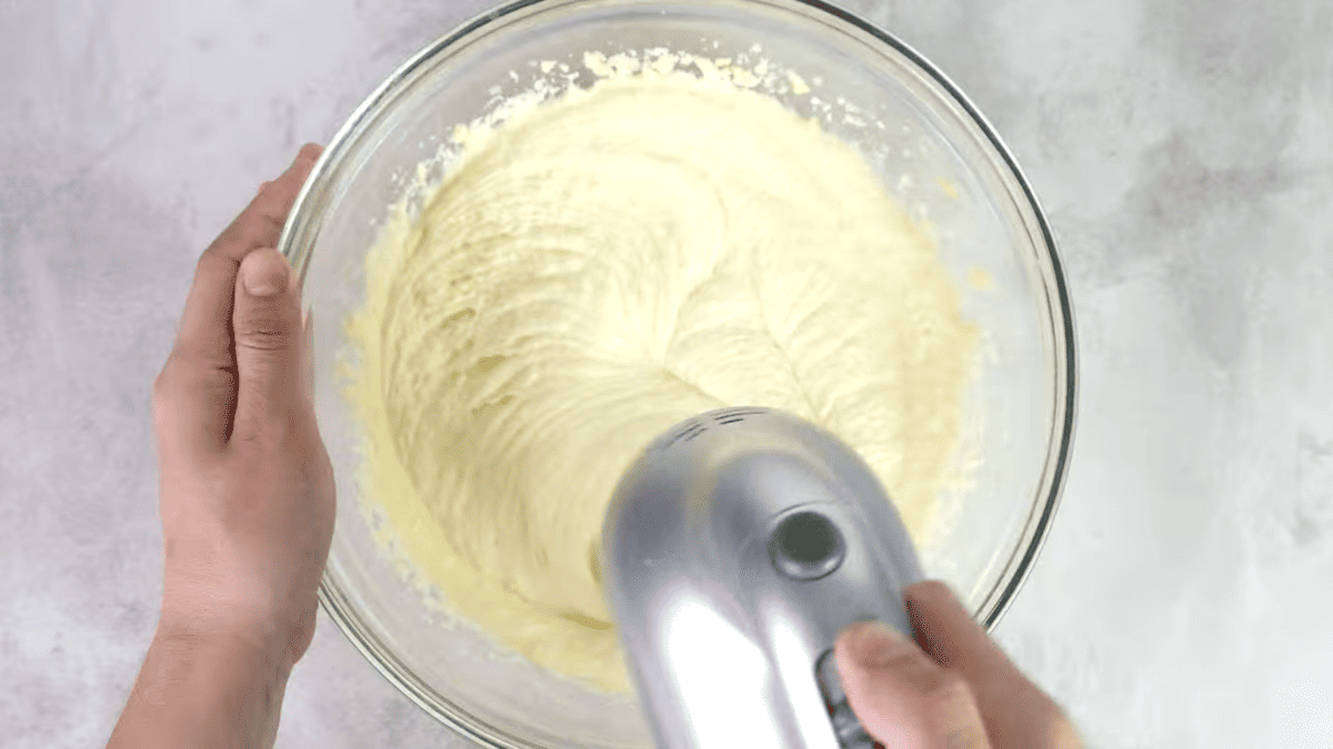 a hand mixer beating cake batter in a glass bowl.
