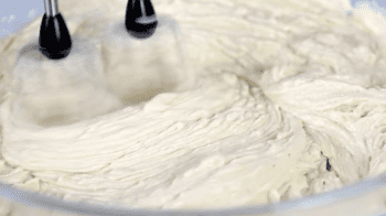 vanilla extract beaten into cake batter in a glass bowl.