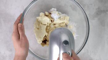 cream cheese, sugar, and vanilla extract in a glass bowl with a hand mixer.