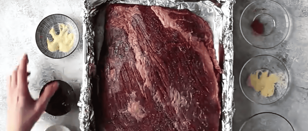 BBQ Brisket with seasonings in an aluminum lined pan.