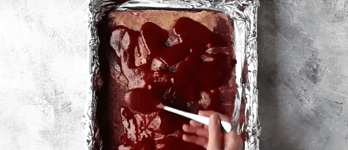 bbq sauce/liquid smoke mixture being spread over the brisket. 