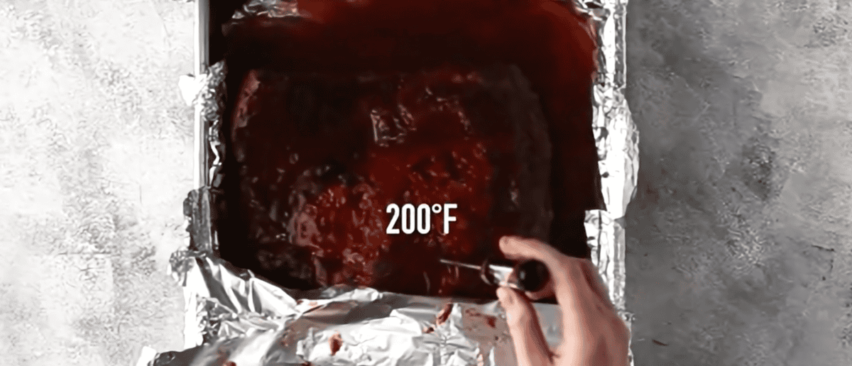 measuring the temperature of the brisket to confirm it is 200 degrees F.