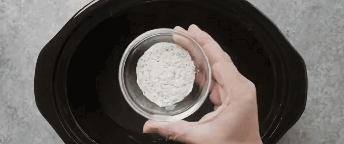Adding seasoning to the crockpot. 