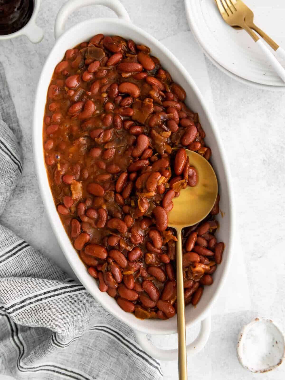 overhead view of instant pot bbq baked beans in a white serving dish with a spoon.