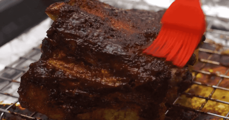 ribs being brushed with barbeque sauce.