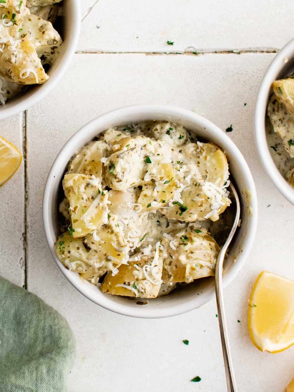 overhead view of pesto potato salad in a white bowl with a fork.