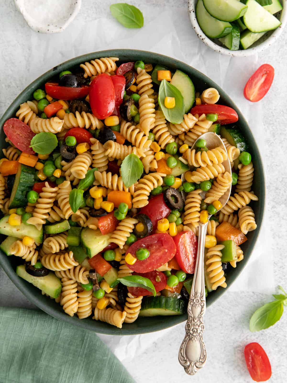 overhead view of rainbow veggie pasta salad in a gray bowl with a spoon.