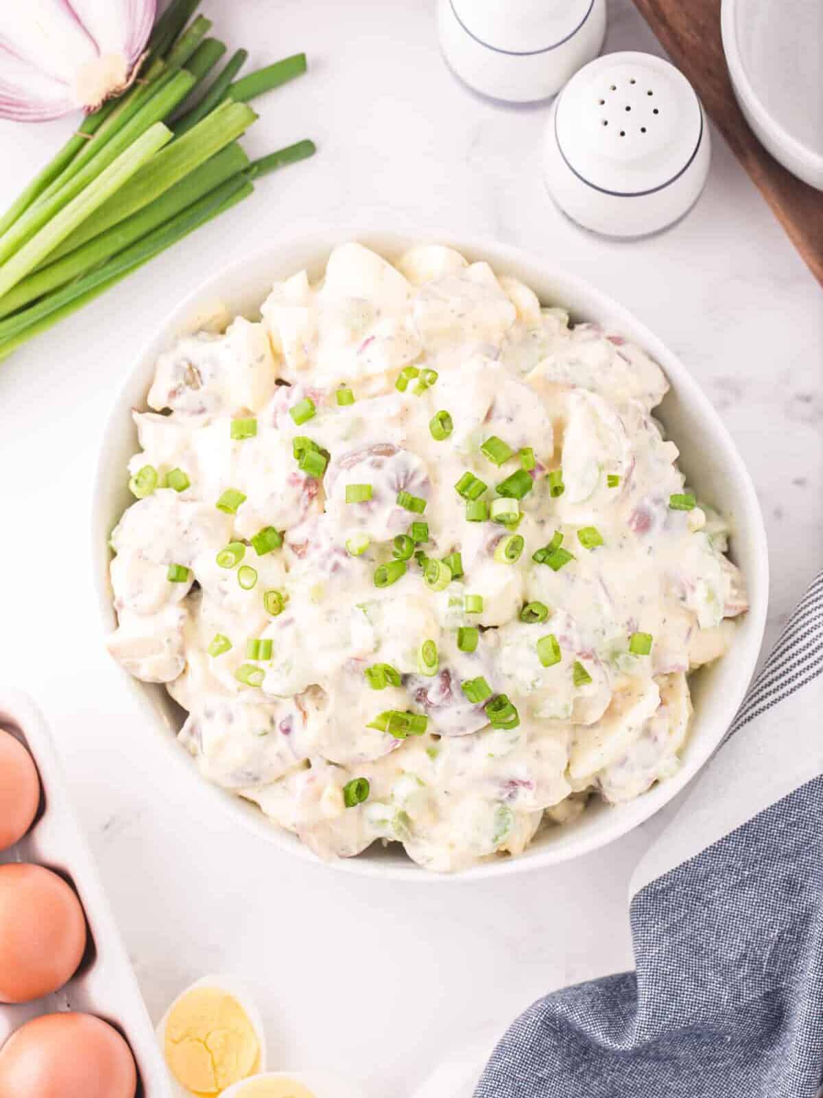 overhead view of ranch potato salad in a white bowl.