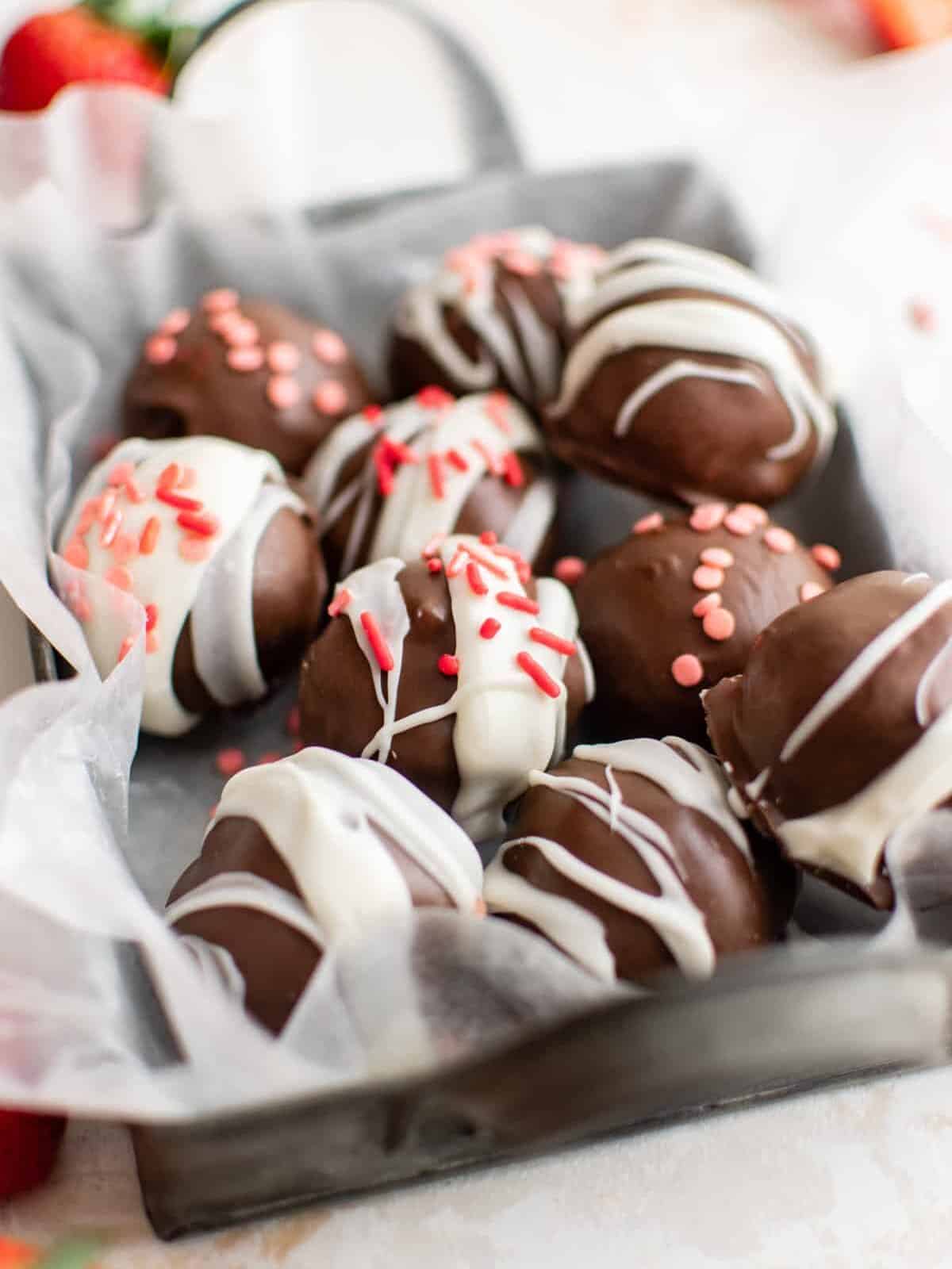 three-quarters view of strawberry truffles in a small parchment lined basket.