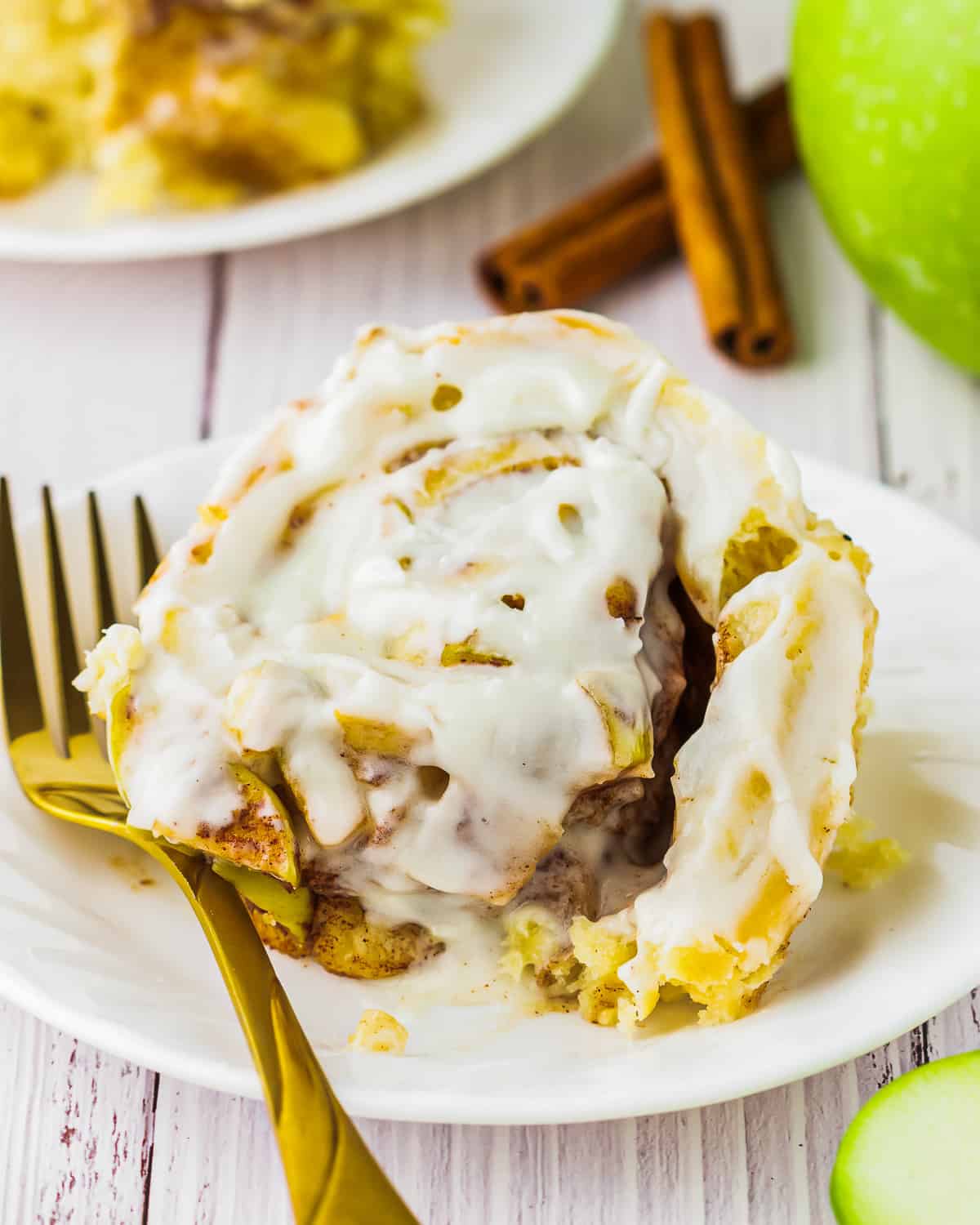 apple cinnamon rolls with cream cheese icing on a plate.