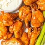 Buffalo wings on a plate with celery and blue cheese dip.