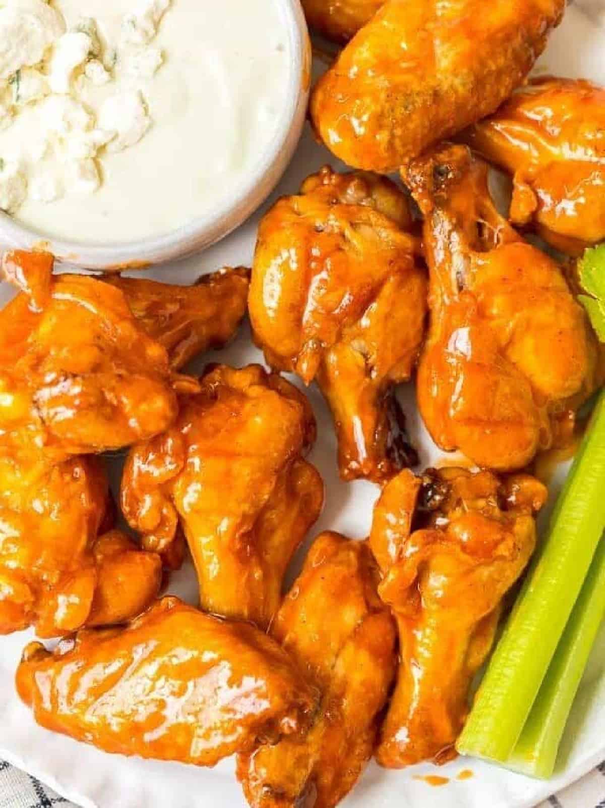 Buffalo wings on a plate with celery and blue cheese dip.