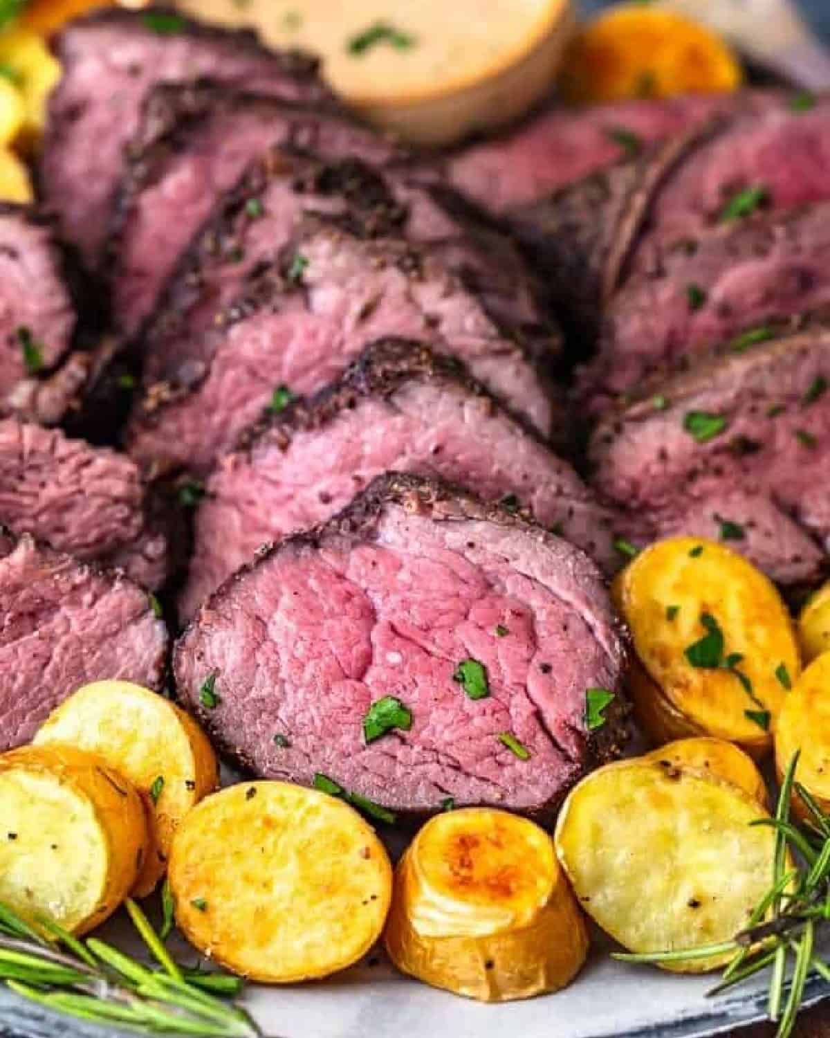 beef tenderloin on platter with potatoes