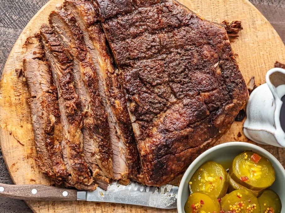 bbq ribs on a cutting board with a knife and pickles.