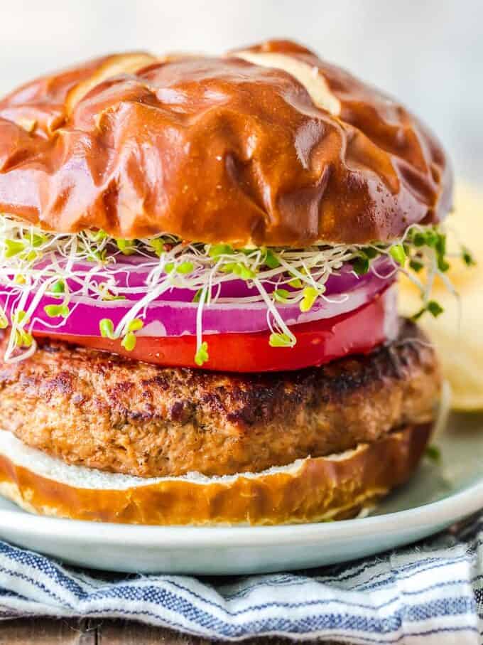 a burger with onions and sprouts on a plate.