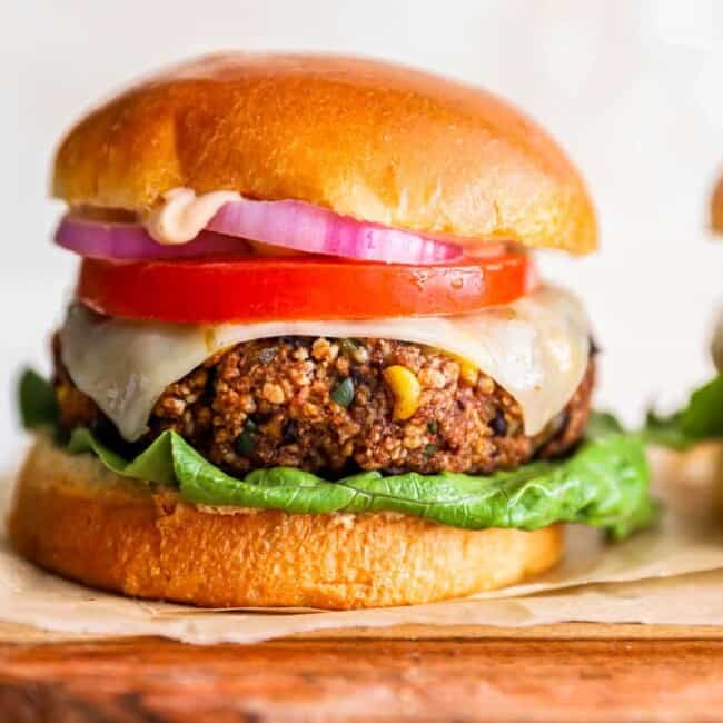 two veggie burgers on a wooden cutting board.