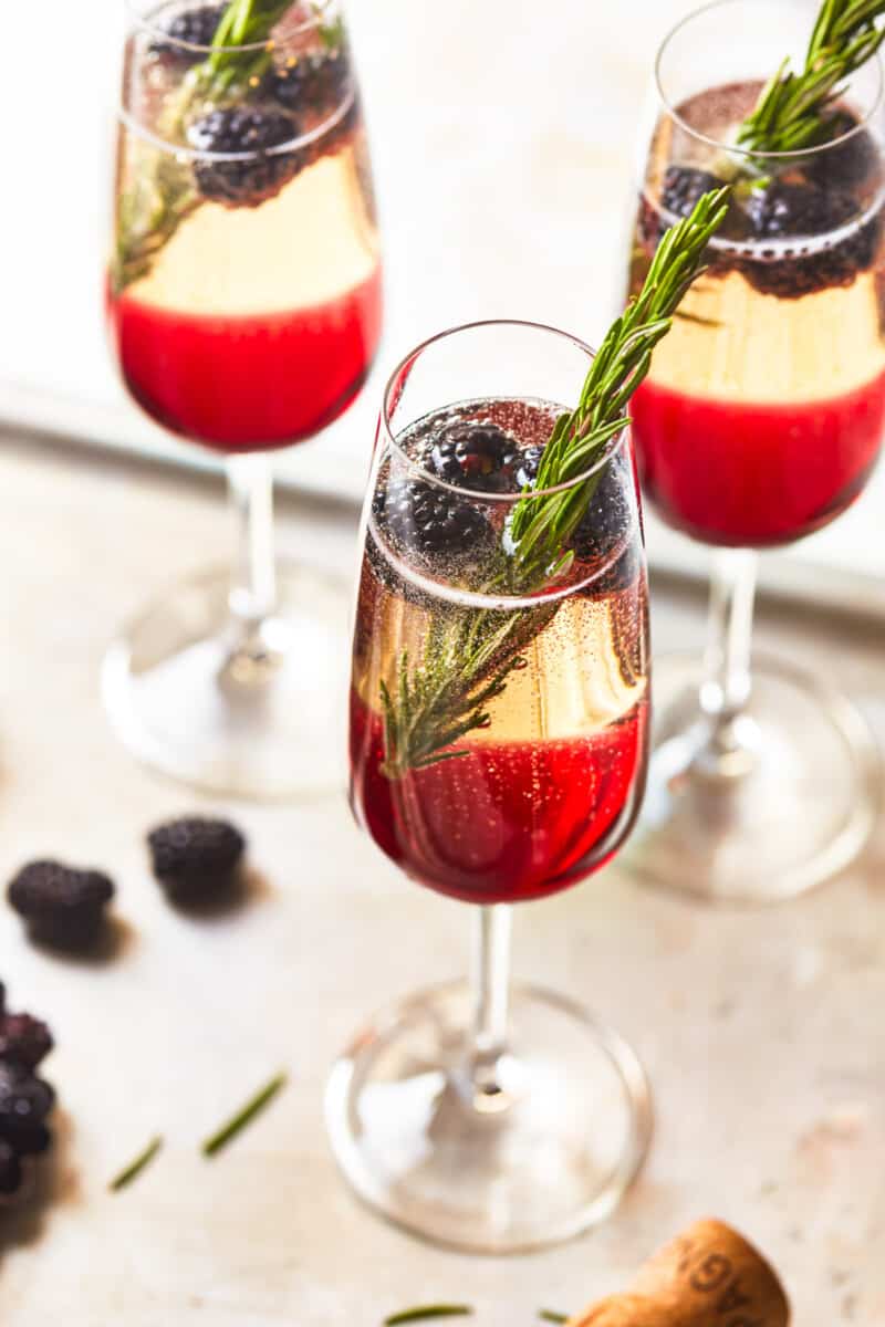 three-quarters view of 3 blackberry champagne cocktails on a metal tray.