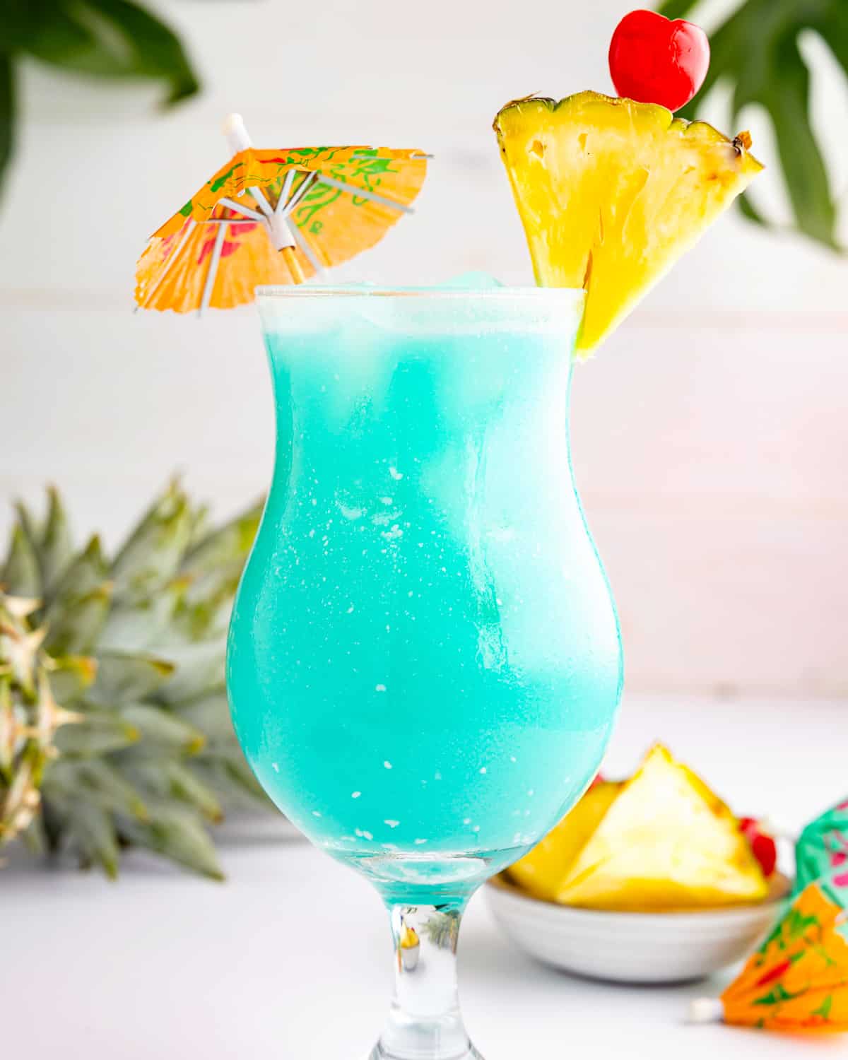 a blue Hawaiian cocktail drink with pineapple garnishes in a glass.