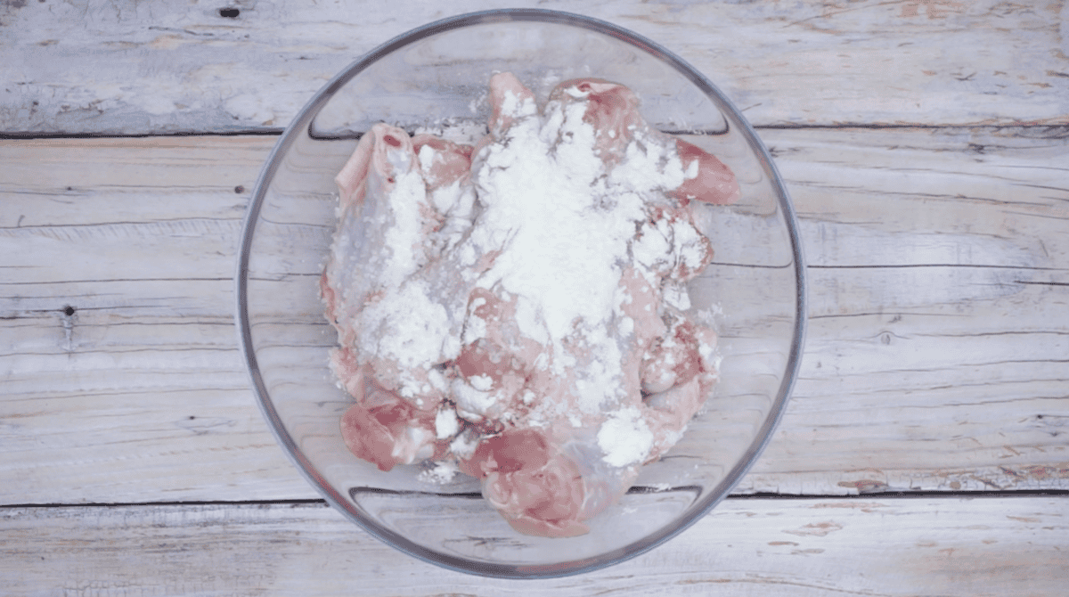 chicken wings topped with baking powder in a glass bowl.