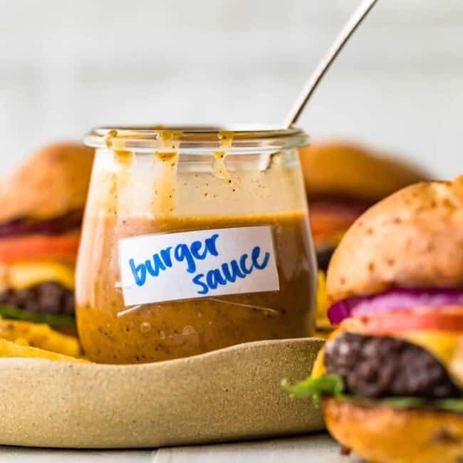 burger sauce in a cup with a spoon and burgers beside it