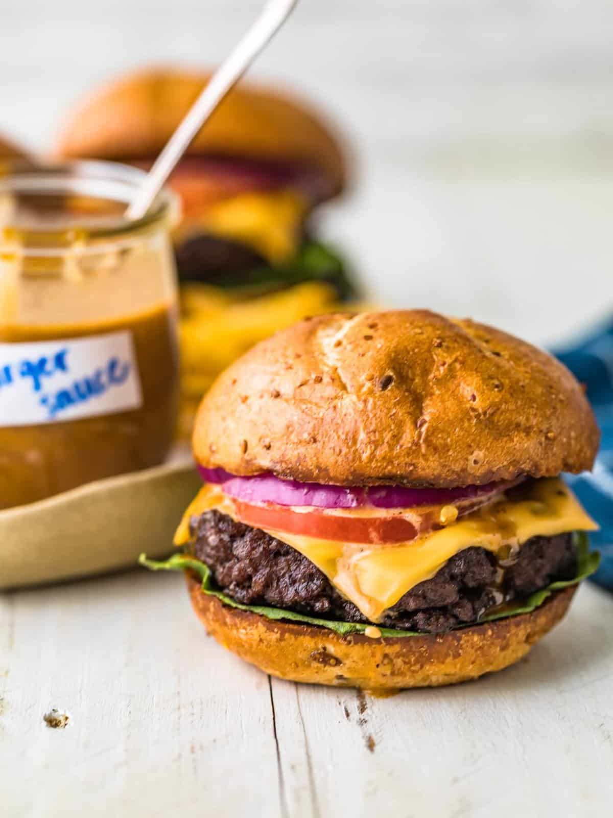 a cheeseburger next to a jar of special burger sauce