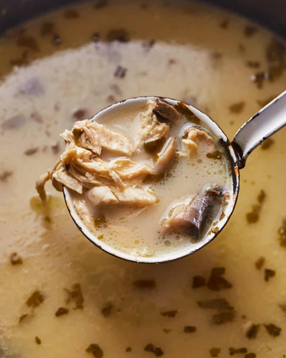 close up of a ladle scooping Thai coconut chicken soup from a Dutch oven.