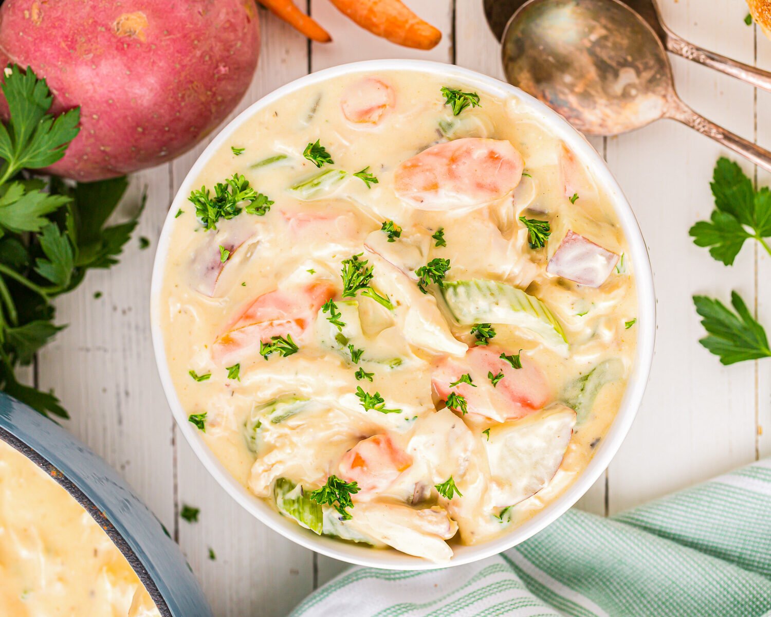 a bowl of chicken chowder with carrots and potatoes.
