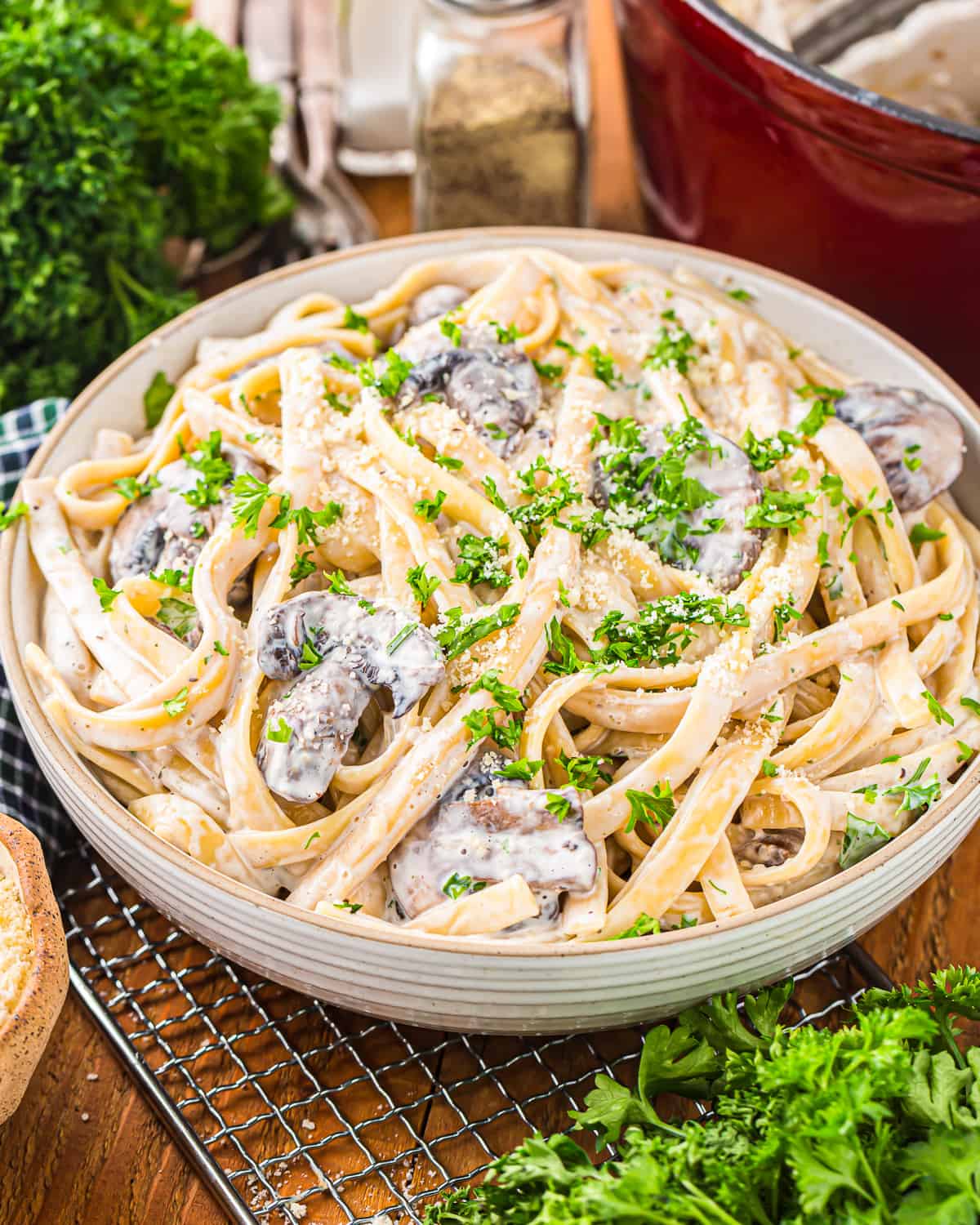 a serving bowl of pasta with mushrooms and parsley in a creamy pasta sauce.