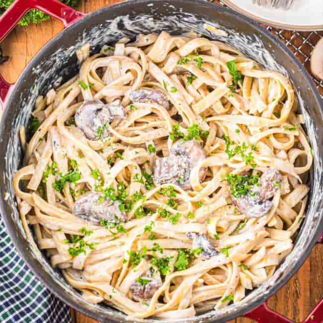 a pan of pasta with mushrooms and parsley.