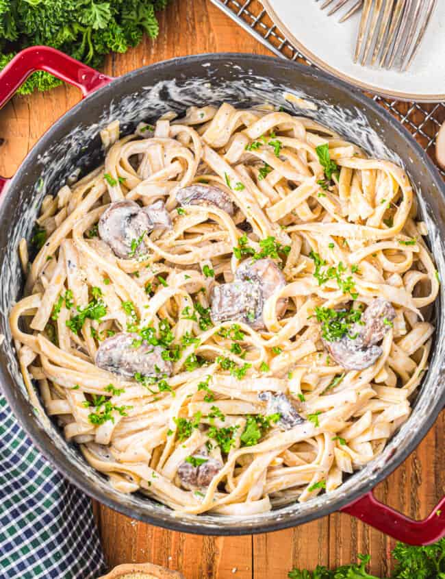 a pan of pasta with mushrooms and parsley.