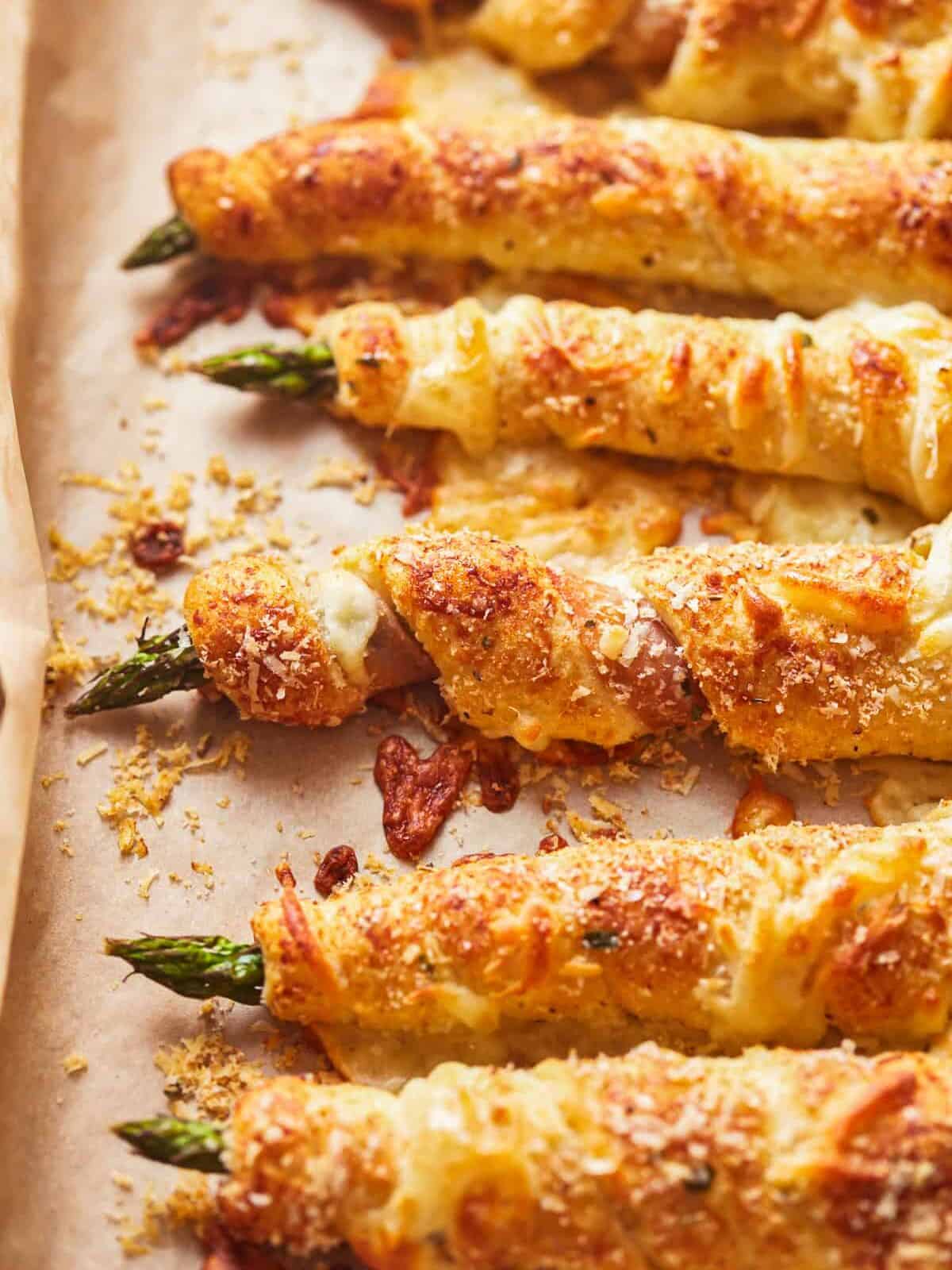 three-quarters view of asparagus crescent rolls pointing east-west on parchment paper.