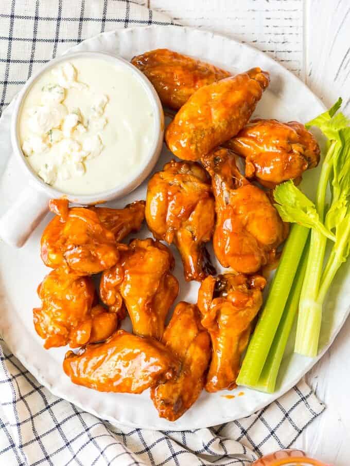 A plate of baked buffalo wings with blue cheese ranch and celery