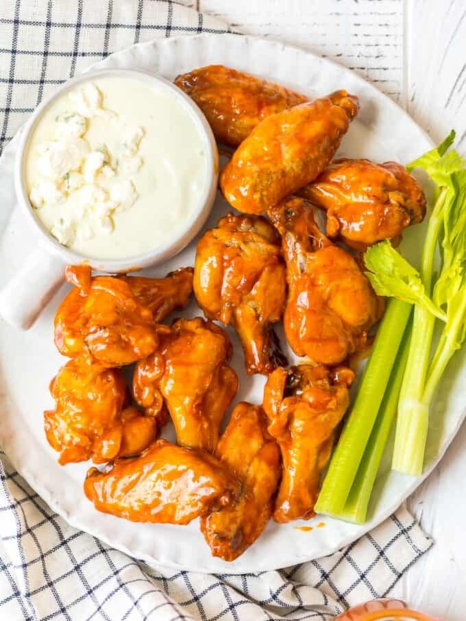 Baked Buffalo Wings are a tasty alternative to typical fried buffalo wings (and a bit healthier too!). These crispy baked chicken wings are covered in our homemade buffalo sauce for the perfect hot and spicy flavor. Baked Buffalo Chicken Wings are a real crowd pleaser and perfect for game day parties. You're going to love these crispy oven baked buffalo wings! A plate of baked buffalo wings with blue cheese ranch and celery