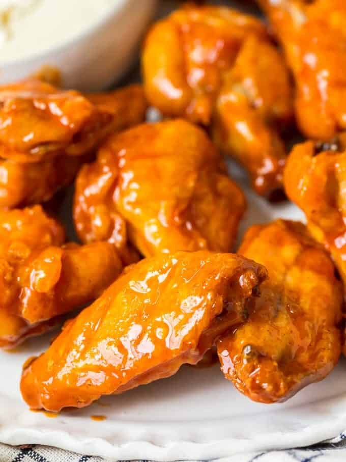 Baked Buffalo Wings are a tasty alternative to typical fried buffalo wings (and a bit healthier too!). These crispy baked chicken wings are covered in our homemade buffalo sauce for the perfect hot and spicy flavor. Baked Buffalo Chicken Wings are a real crowd pleaser and perfect for game day parties. You're going to love these crispy oven baked buffalo wings! Crispy baked chicken wings with buffalo sauce