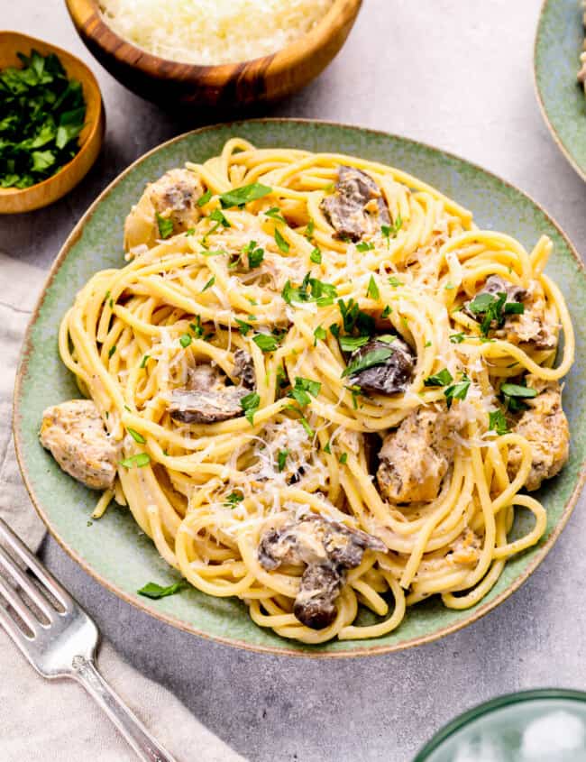 a plate of spaghetti with mushrooms and parmesan cheese.
