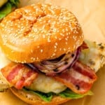 Two chicken burgers with bacon and onions.