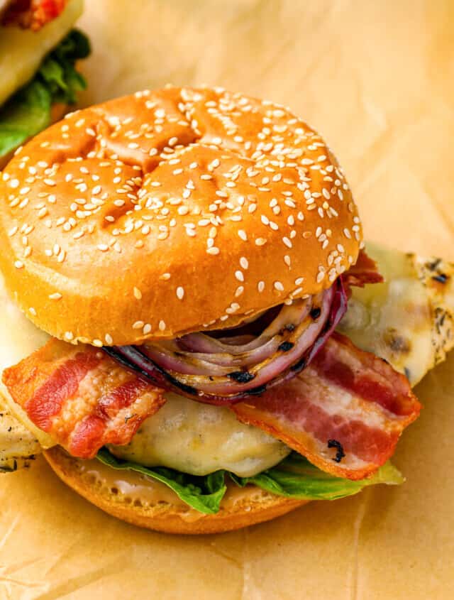 Two chicken burgers with bacon and onions.