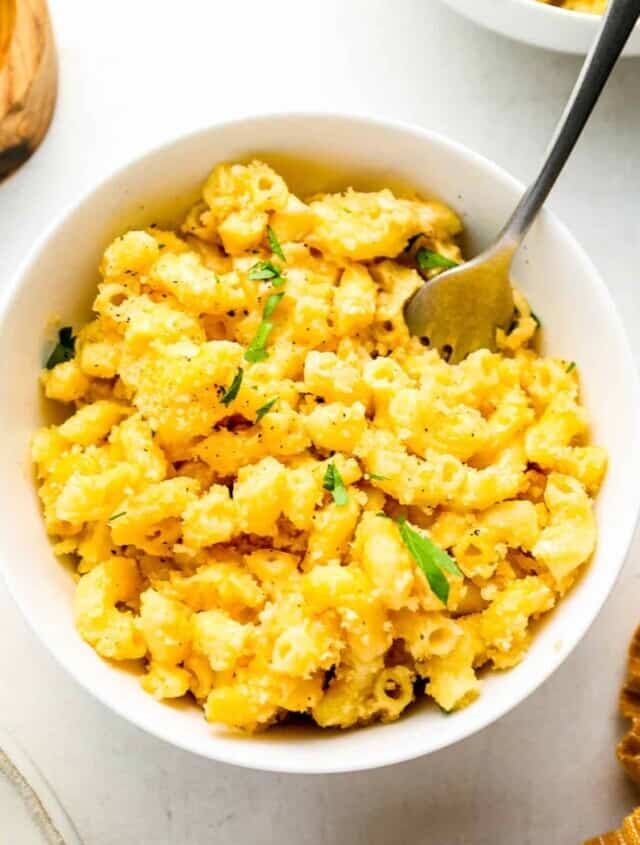 close up overhead view of a serving of smoked mac and cheese in a white bowl with a fork.