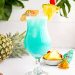 a blue hawaiian cocktail with pineapples and umbrellas.