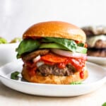 a burger on a plate with vegetables and sauce.