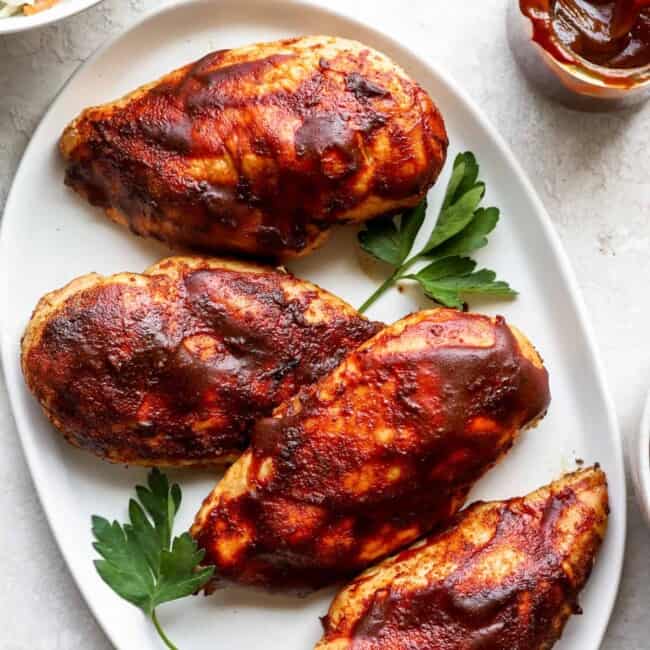 bbq chicken breasts on a white plate.