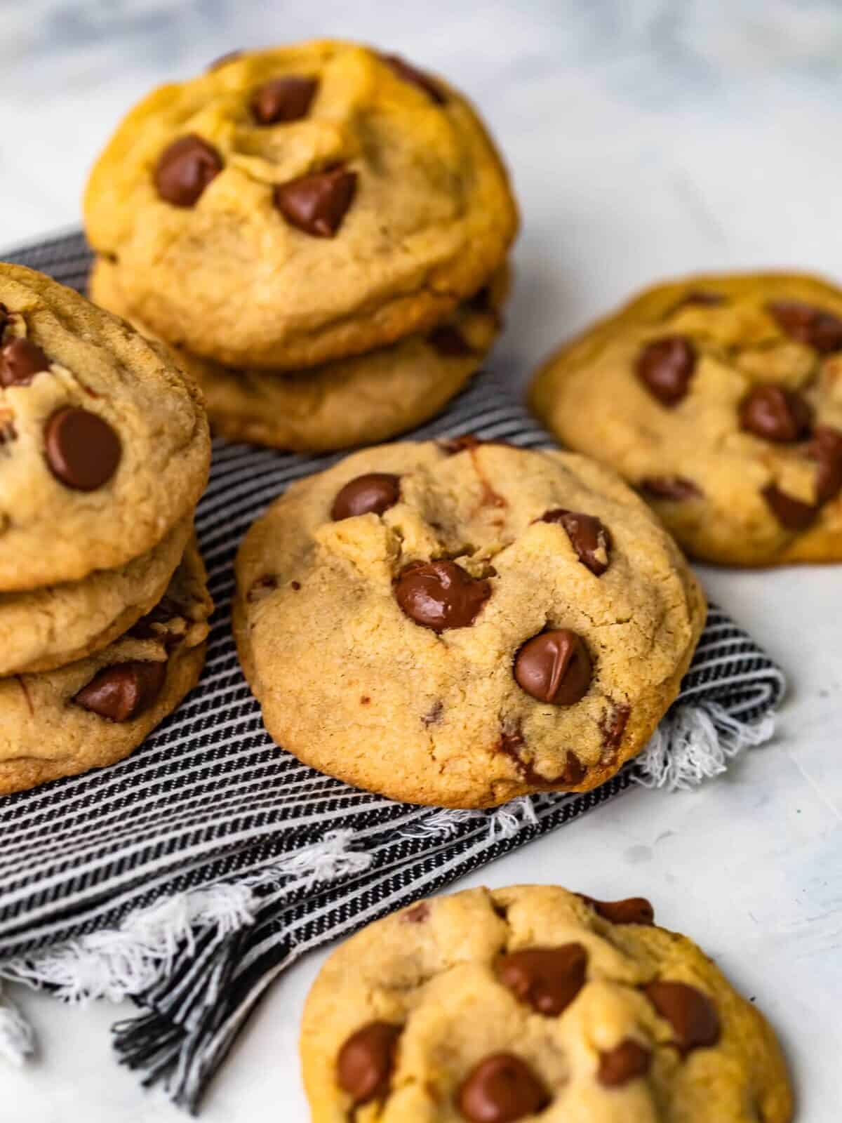 soft and chewy chocolate chip cookies stacked on a dish towel
