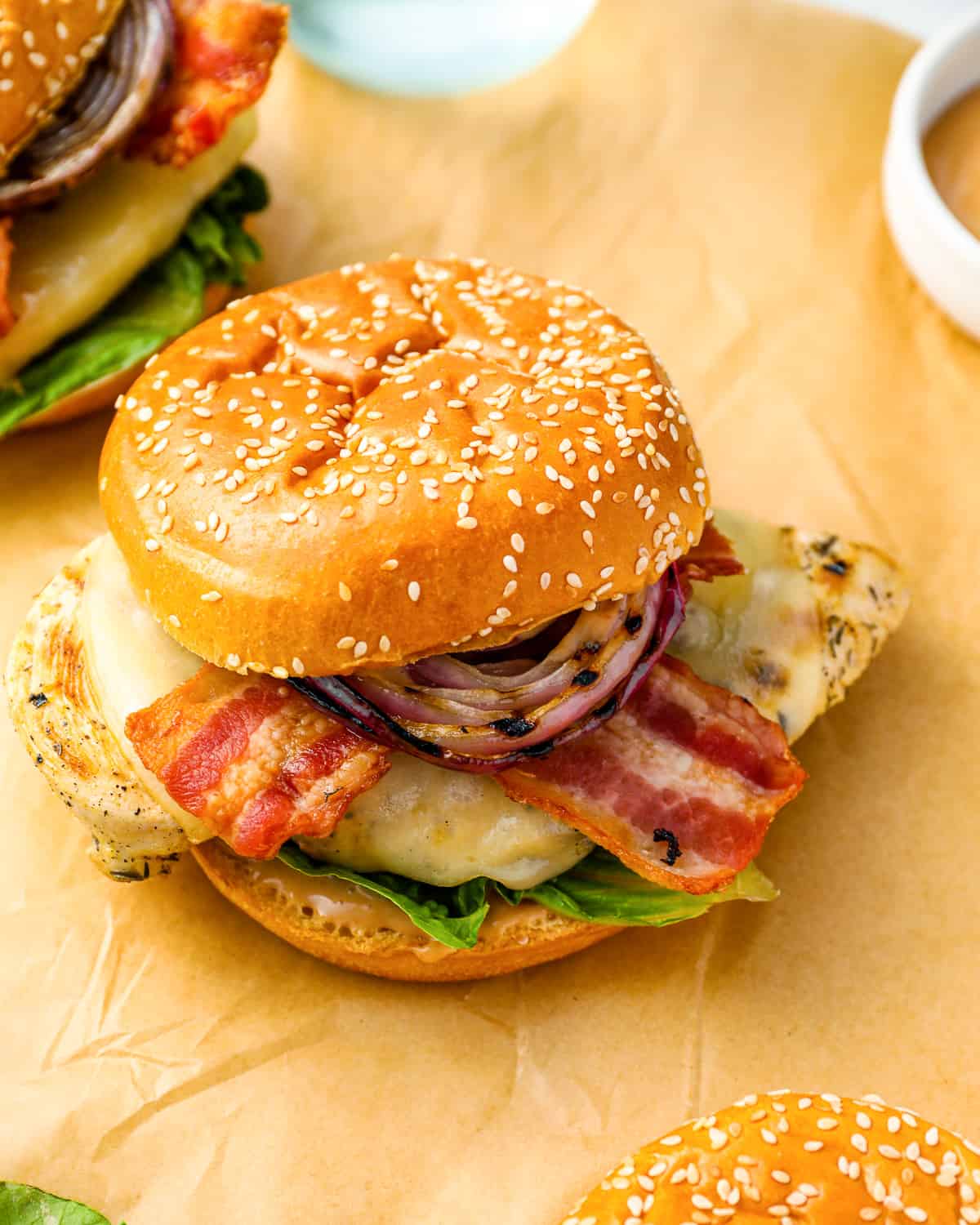 three-quarters view of a grilled chicken sandwich on parchment.