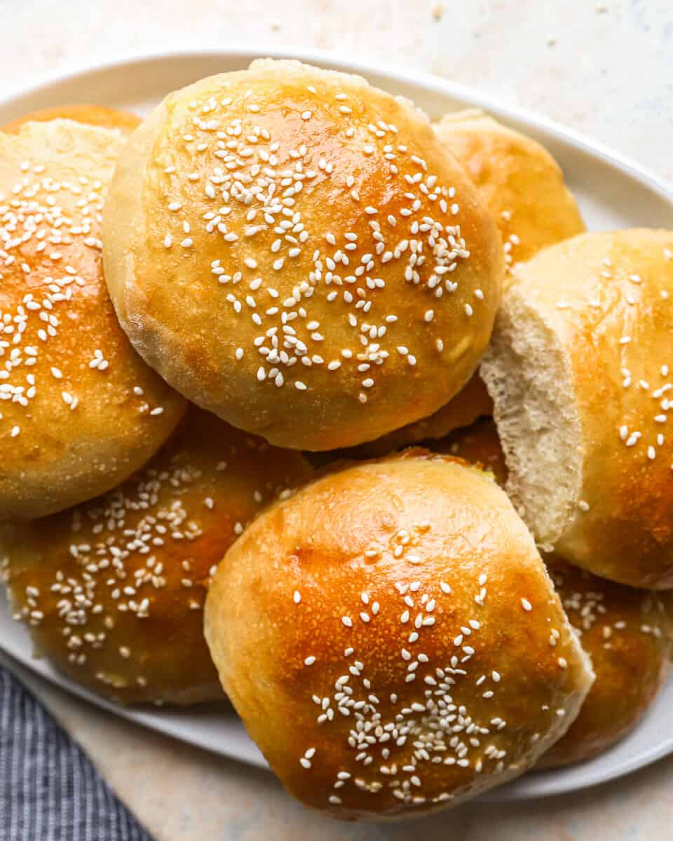 hamburger buns with sesame seeds on a plate.