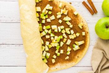 an apple pie with cinnamon and apples on a wooden table.