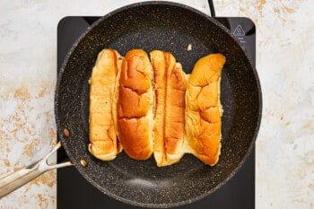 hot dog buns toasting face down in an oil pan.