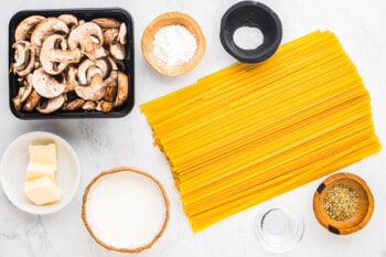 ingredients for creamy mushroom pasta arranged on a white background