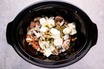 a crock pot filled with vegetables and mushrooms.